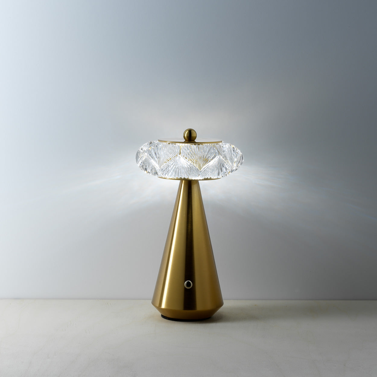Gold table lamp with a diamond shape glass on a light gray background