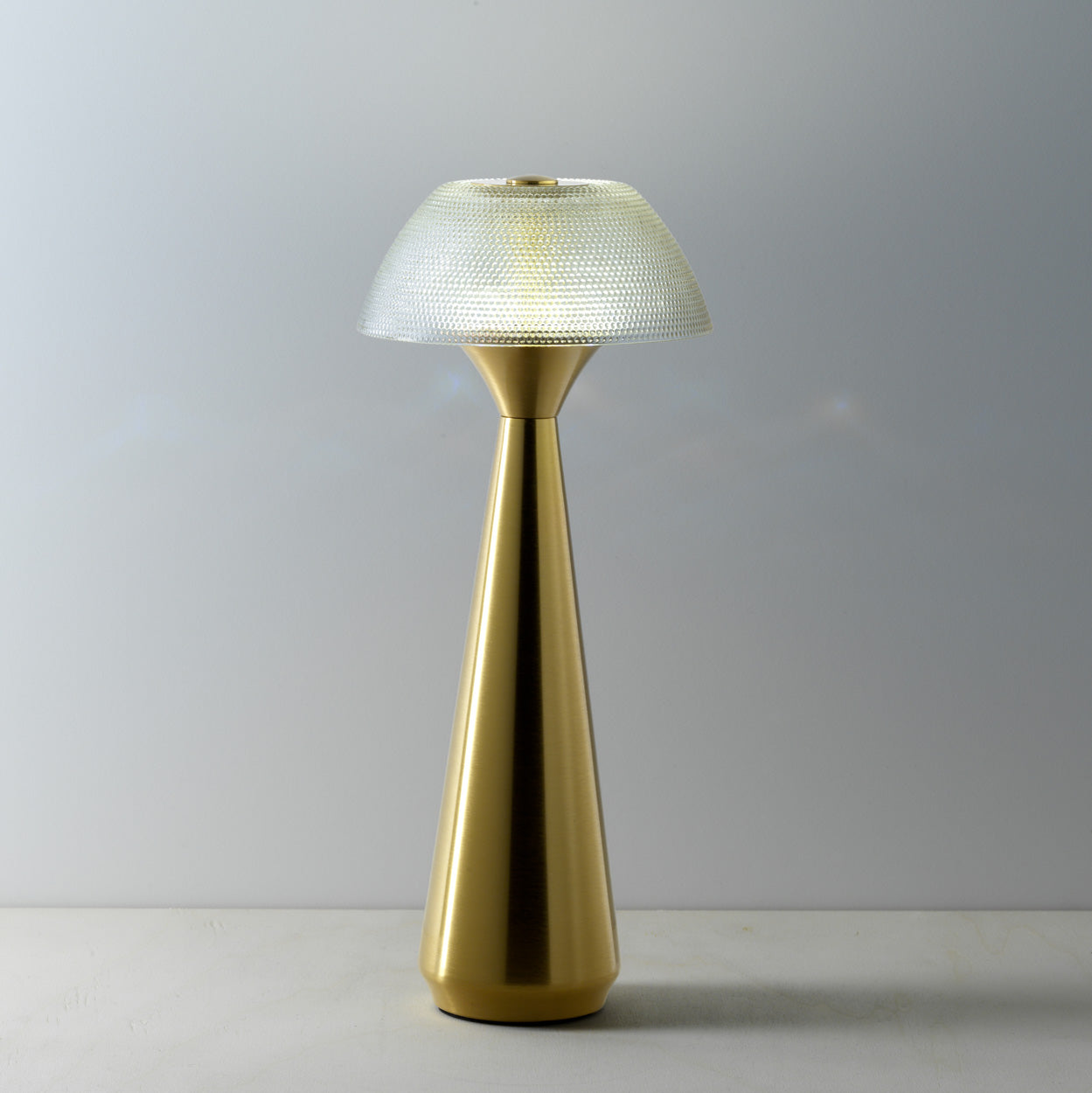 Gold table lamp with textured shade on a gray background