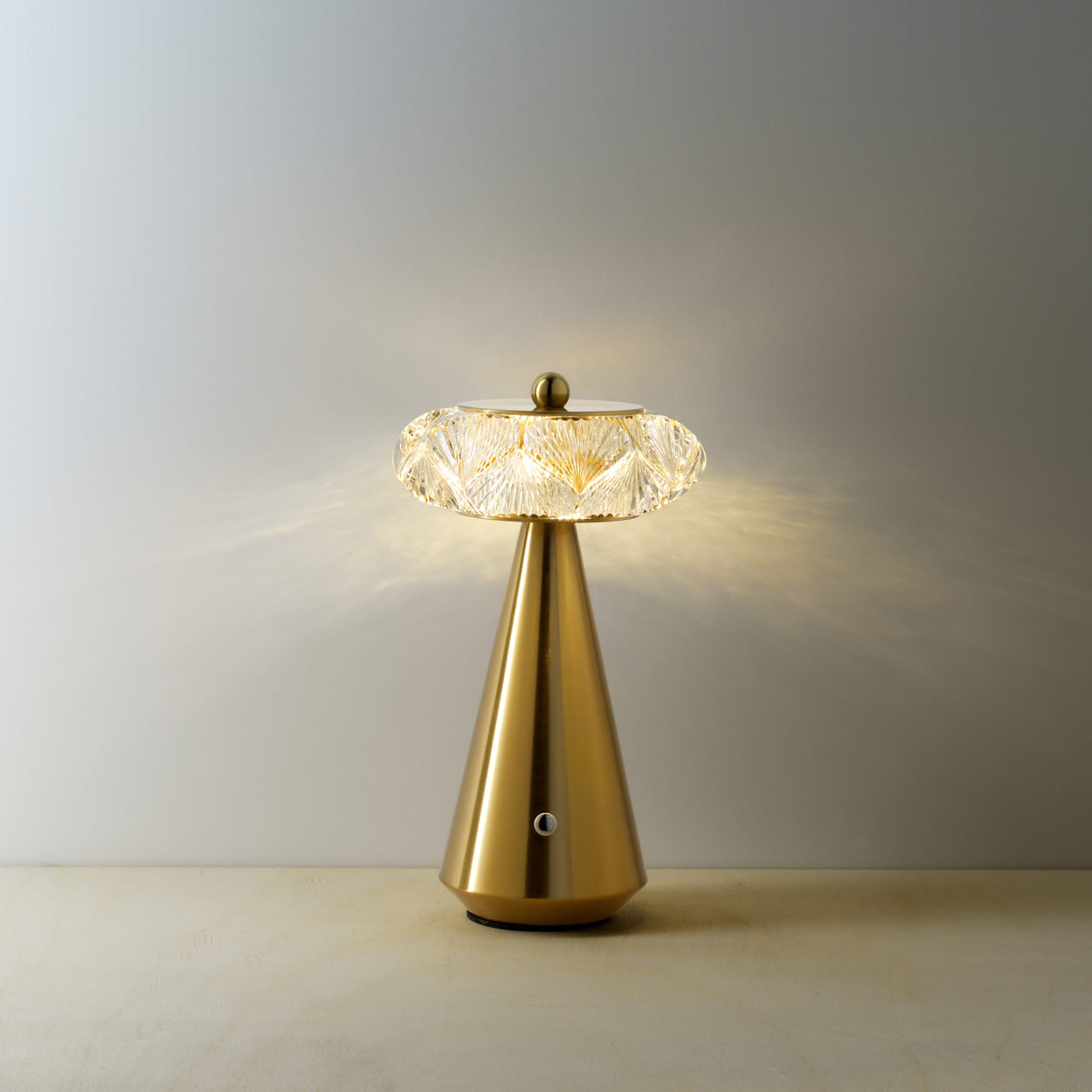 Gold table lamp with diamond shape glass on a warm background