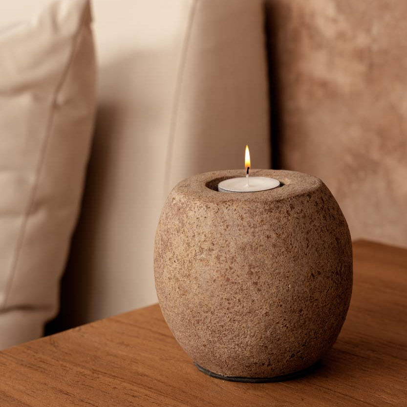 Terracotta candle holder on a wooden surface, with a beige background
