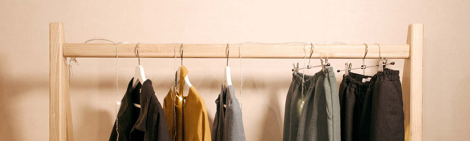 Wooden hangers on a rack on a pastel wall background