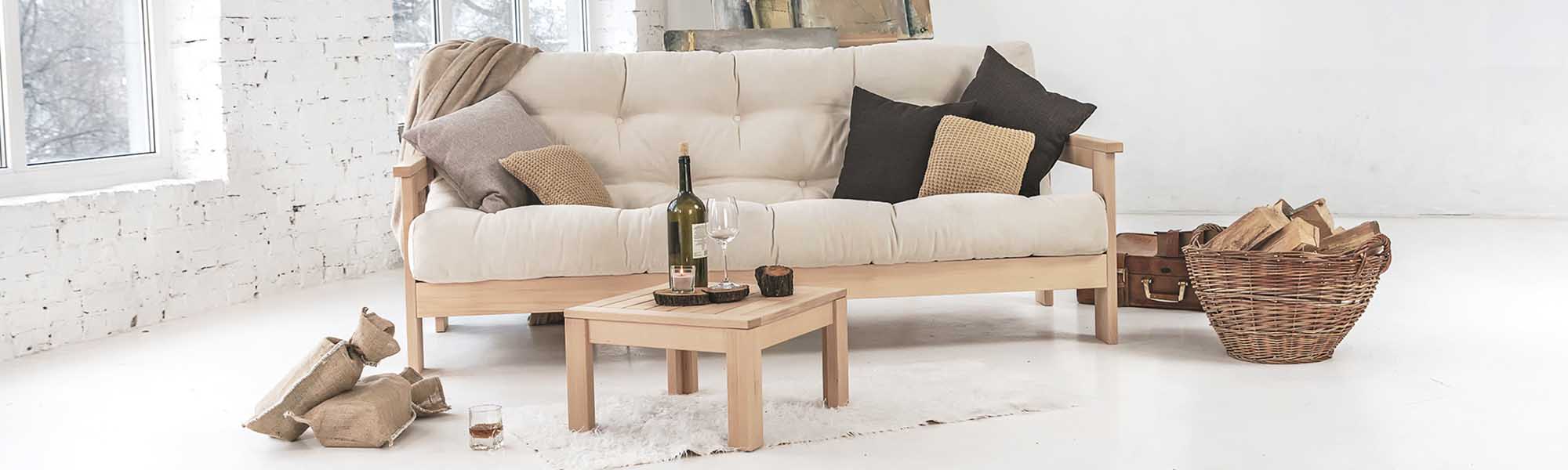 A wooden sofa with a soft cream-colored mattress and a wooden coffee table in a bright living room
