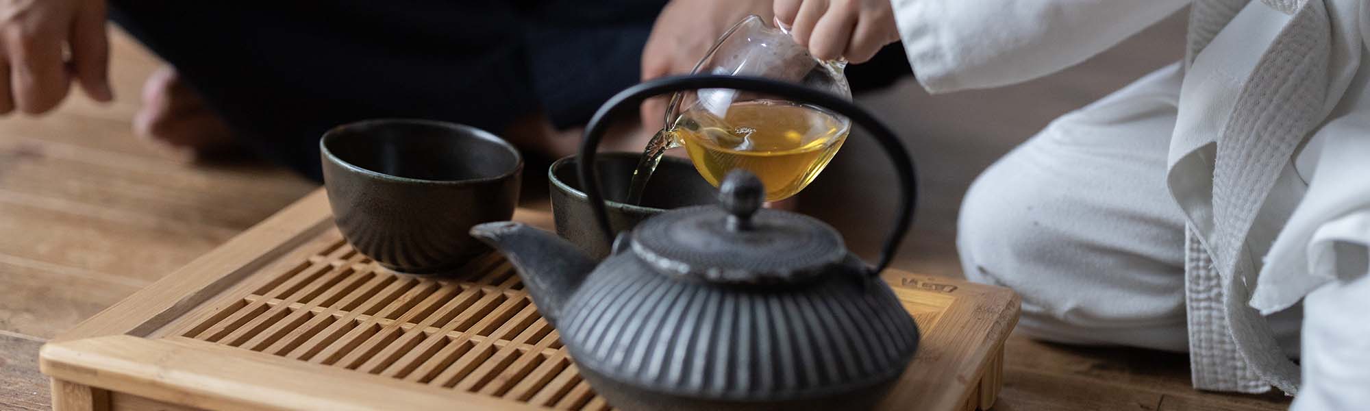 A wooden tea tray with a black teapot and mug on top