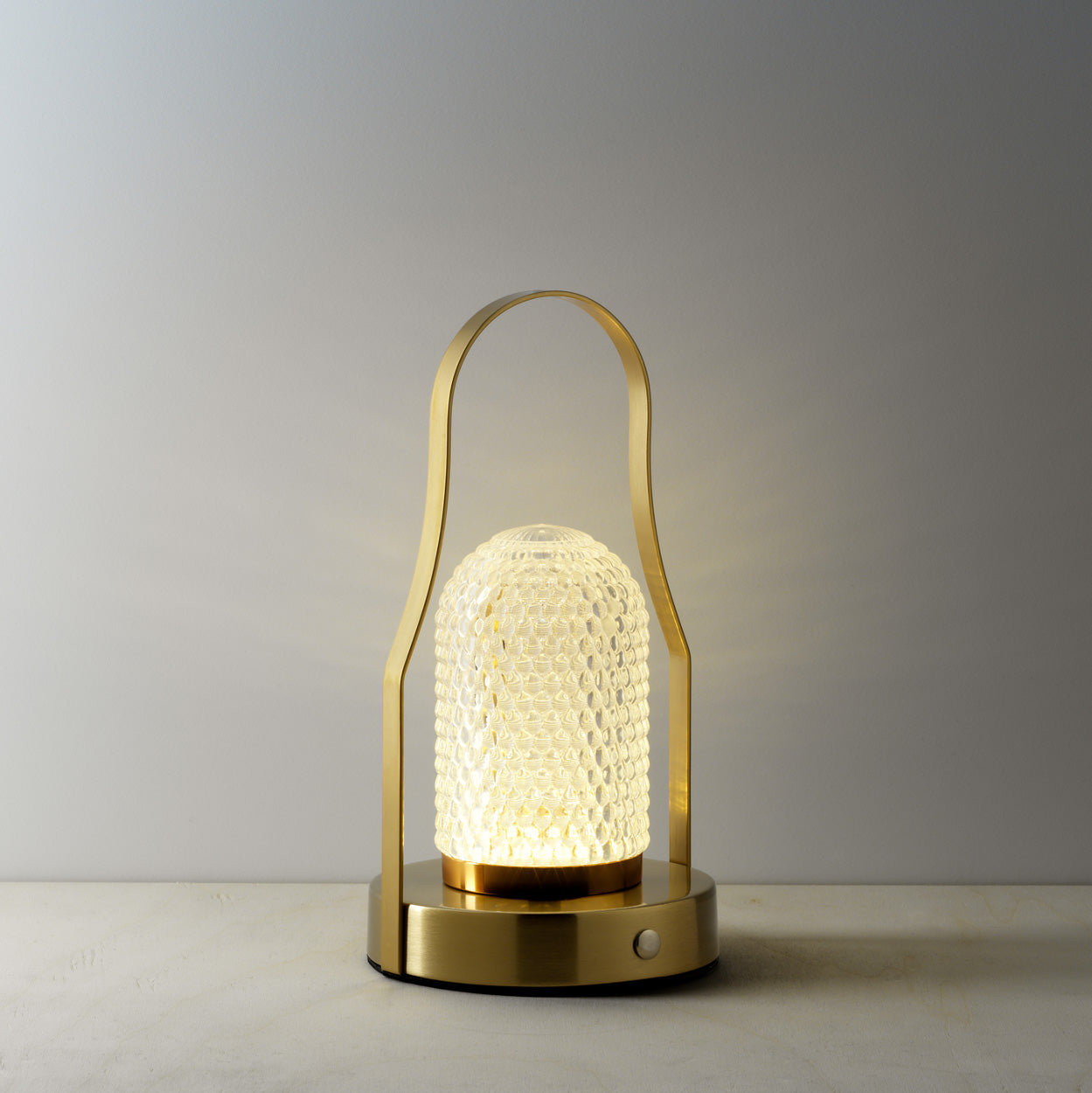 Decorative lamp with textured glass shade and gold metal frame on a warm background