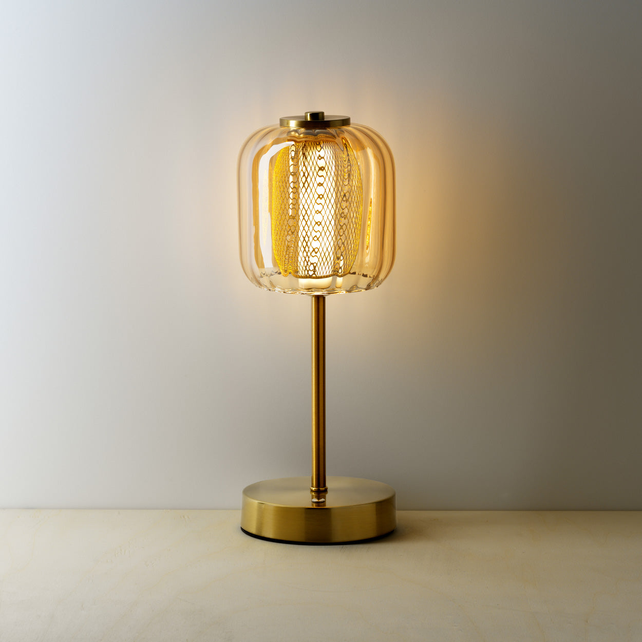 Gold table lamp with a textured glass shade on a warm background