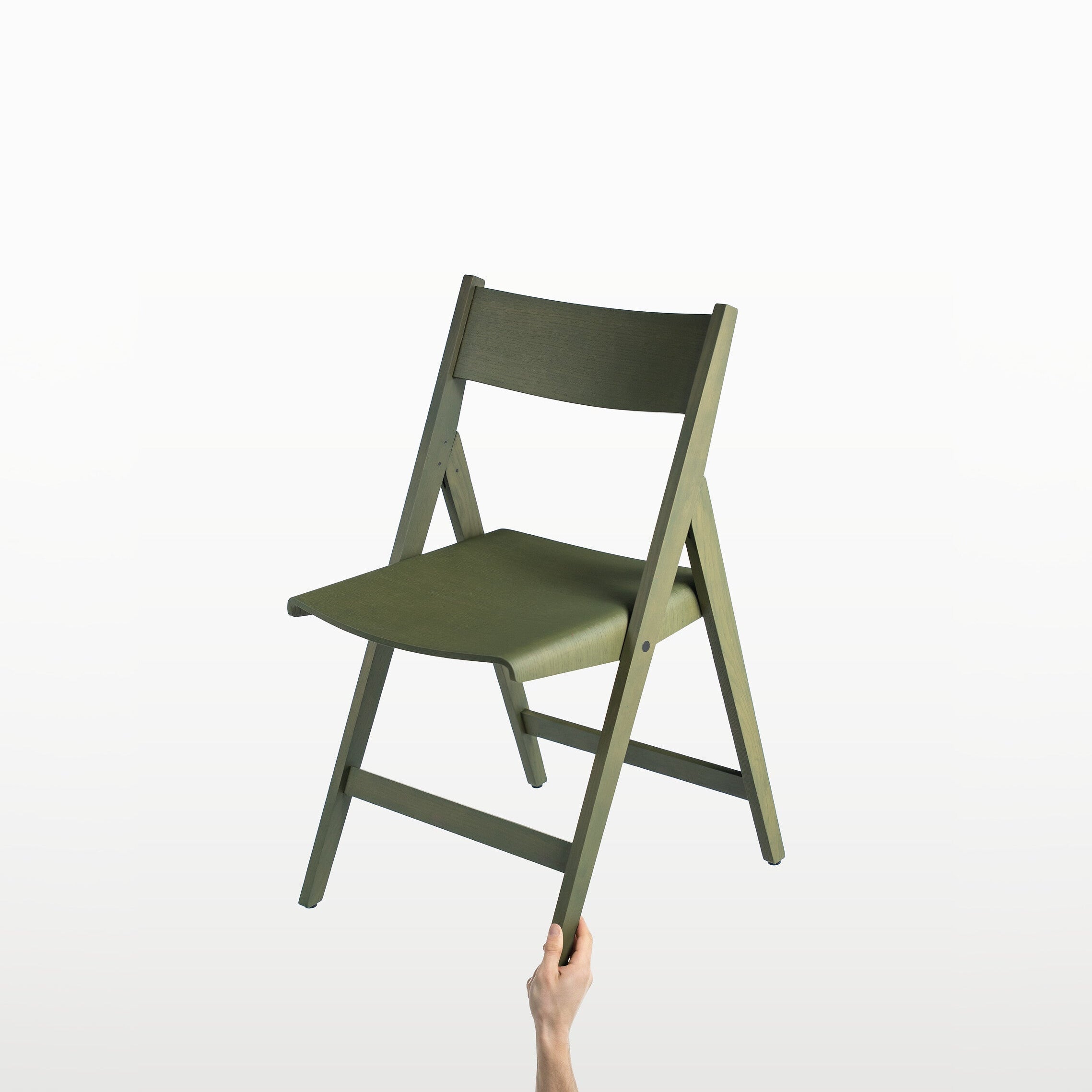 Green THEO folding chair held by a hand against a white background