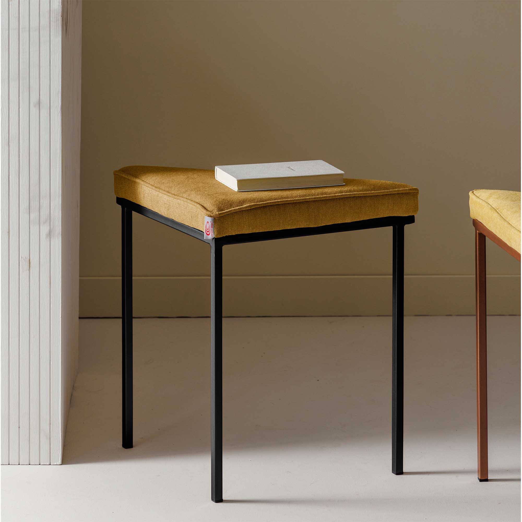 Tripod Stool, Powder-Coated Frame yellow fabric, black frame, interior view with book